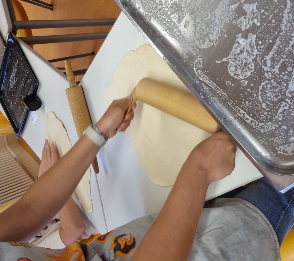 Pizzateig wird von Schüler ausgerollt